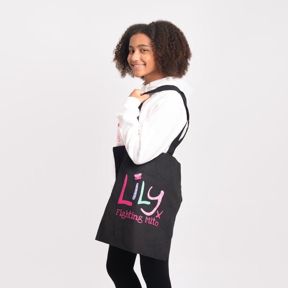 a black cotton bag featuring the Lily Foundation logo and the text fighting mito over a girl's shoulder.