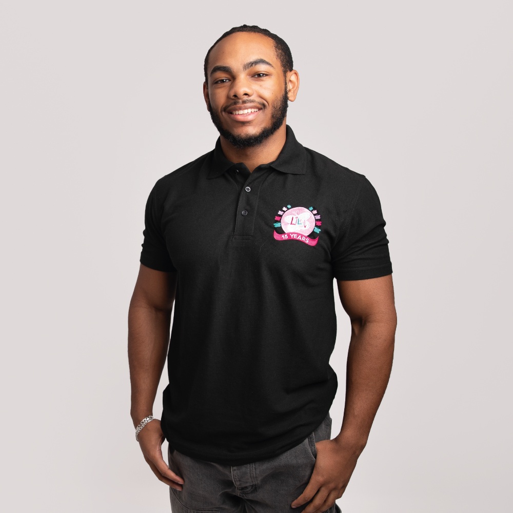A smiling man wearing a black polo shirt featuring the Lily Foundation's 15 Years logo on the chest.
