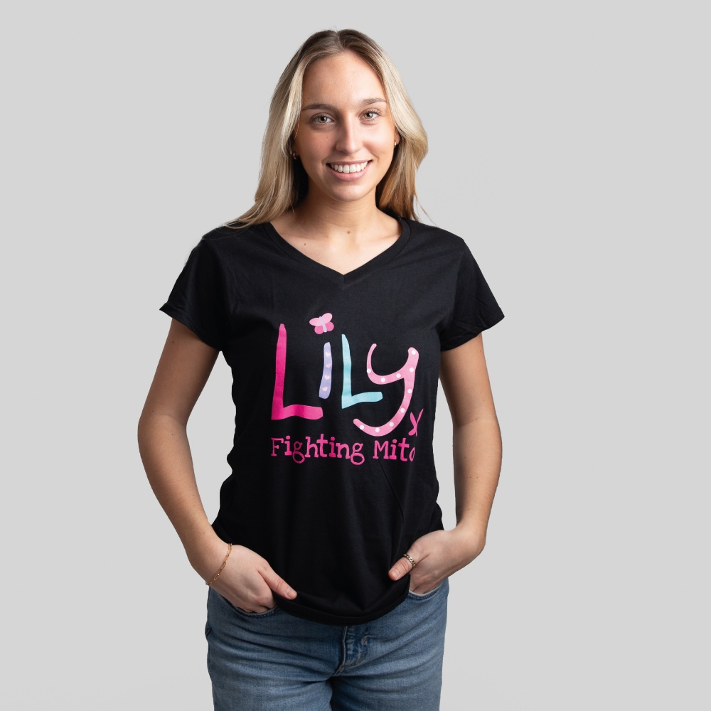 A smiling woman in a black v-necked t-shirt featuring the Lily Foundation logo and fighting mito underneath.