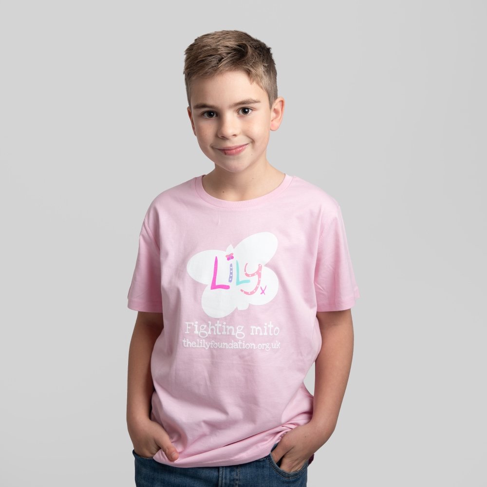 A young boy wearing a pink t-shirt featuring the Lily Foundation butterfly logo & the text Fighting Mito.