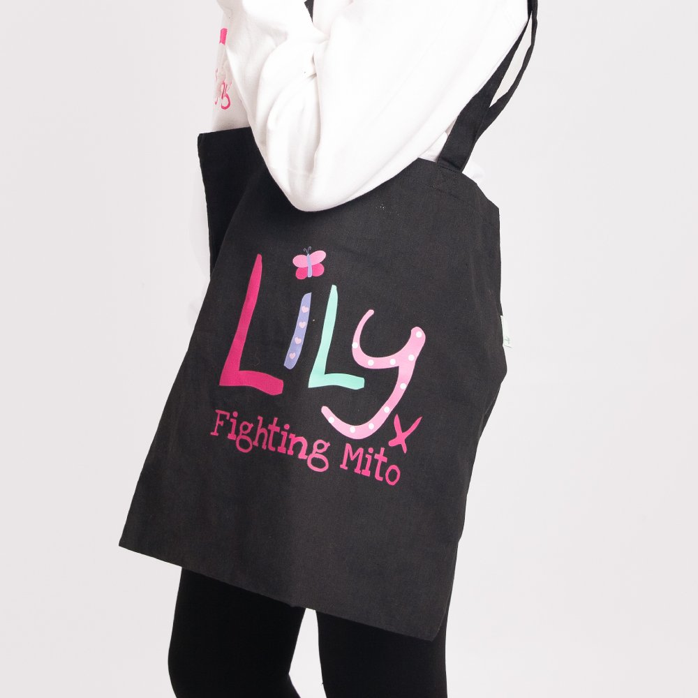 a black cotton bag featuring the Lily Foundation logo and the text fighting mito over a girl's shoulder.