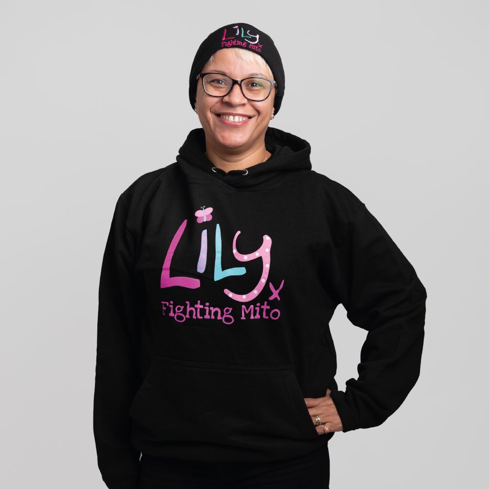 A smiling woman in a black hoodie and matching beanie featuring the Lily Foundation logo and the text fighting mito.