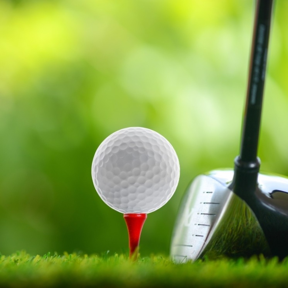 Close-up of a golf ball and the head of a club on a green