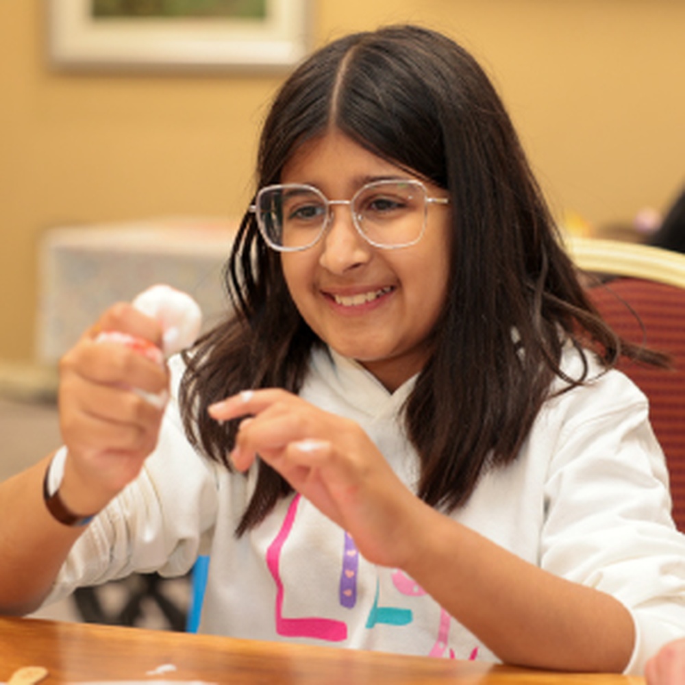 A young mito patient wearing a Lily top doing crafts at the Lily family weekend