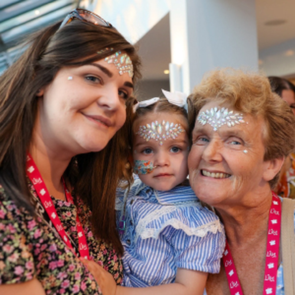 A young mito patient with her mother and grandmother either side of her holding her