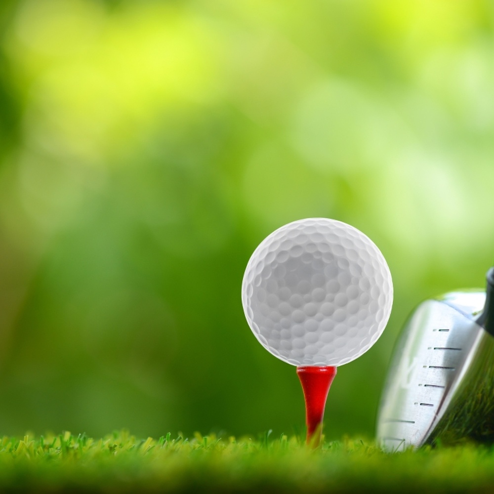 Close-up of a golf ball and the head of a club on a green