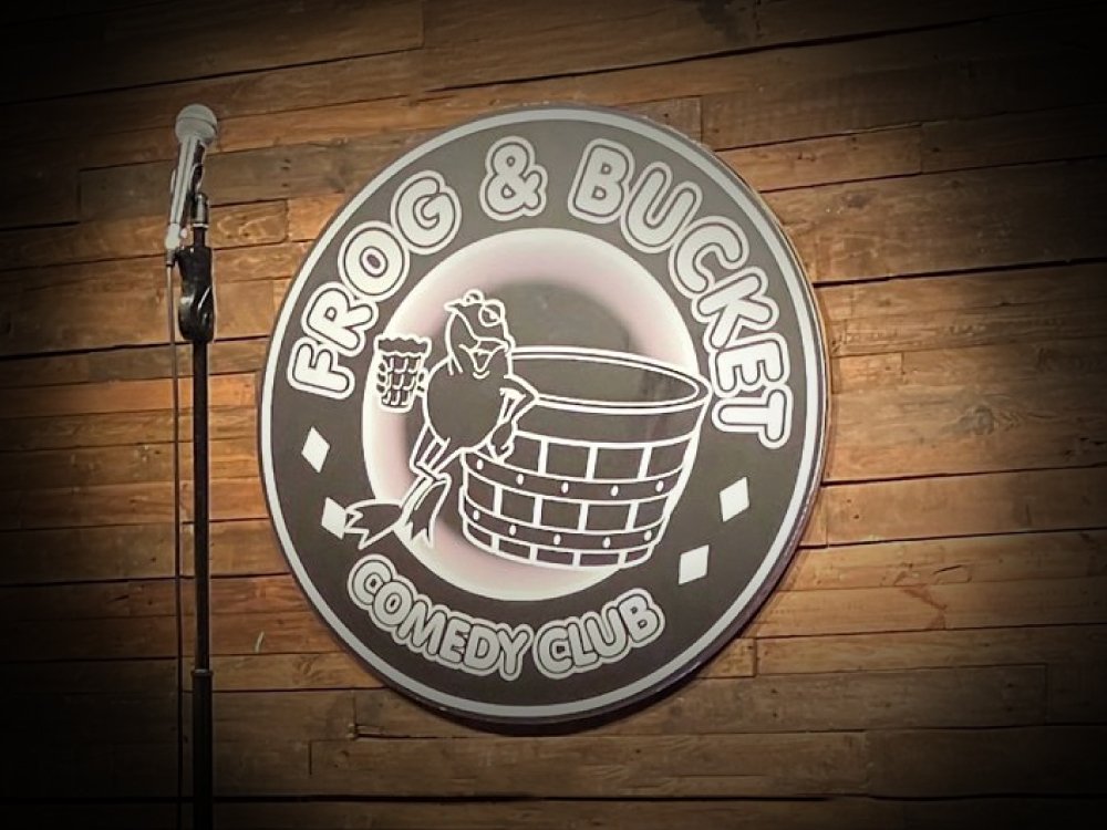 Lily Manchester Comedy Night 2026 – Save the Date - A microphone on stage with the Frog & Bucket logo on the wall behind