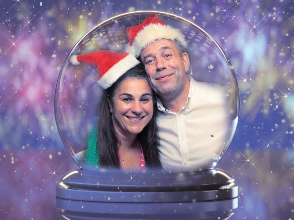 Lily Foundation CEO Liz Curtis and her partner Dave wearing Santa hats and depicted in a snow globe