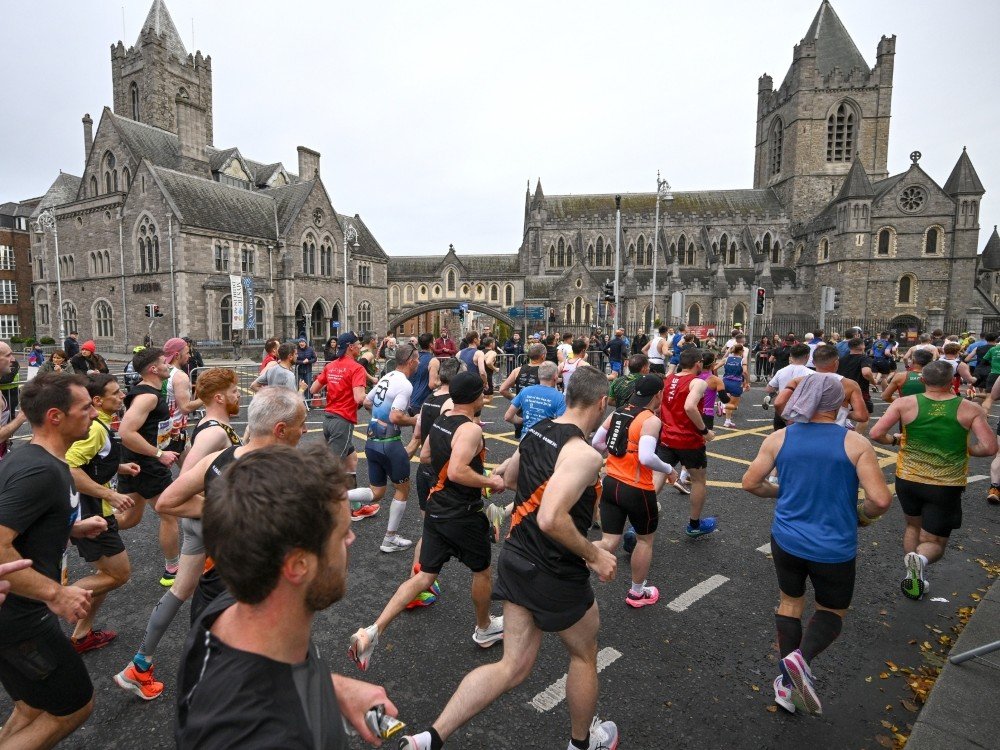 The image shows the backs of a large group of men and women running through Dublin