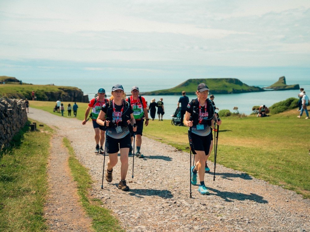 A group of people hiking along a footpath near the coast