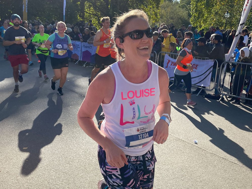 Lady in a Lily Foundation vest and sunglasses running and smiling