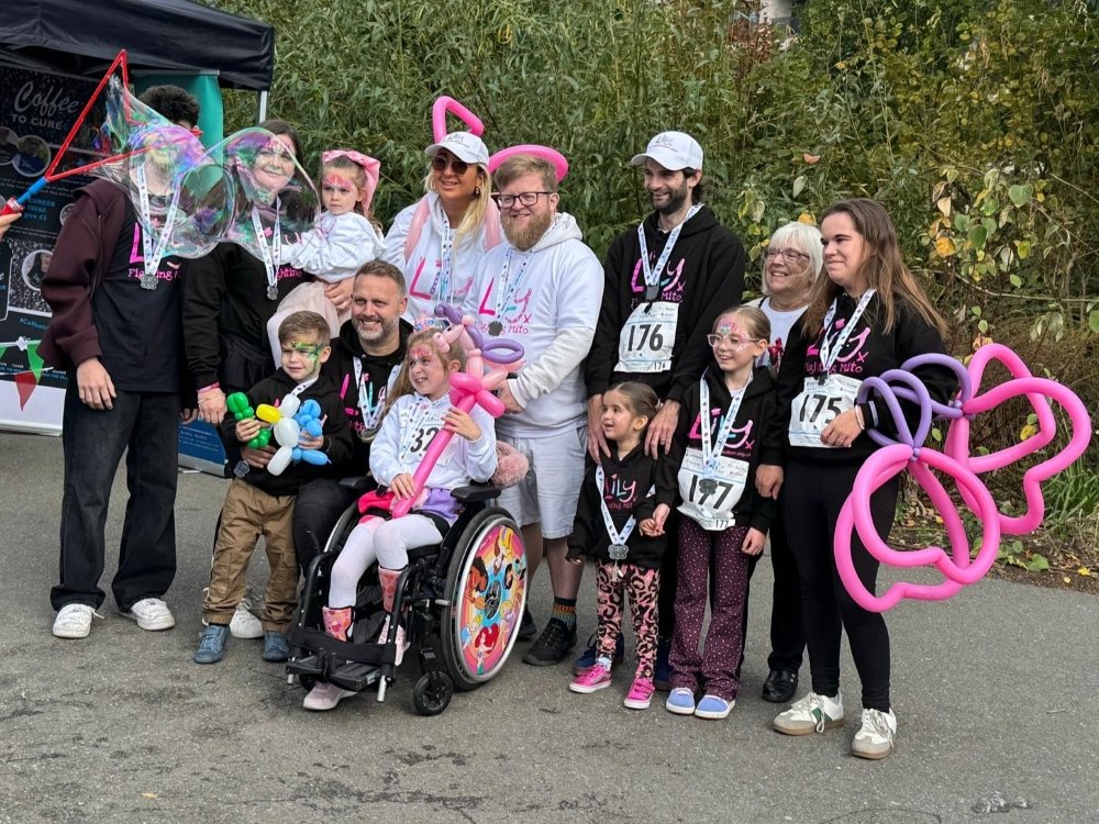 A group of people wearing a range of Lily Foundation tops including one young female in a wheelchair at the front of the group. They are all proudly wearing their finishers medals.