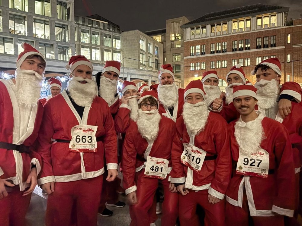 A group of fundraisers dressed in Santa suits and white beards running a Christmas charity Santa run