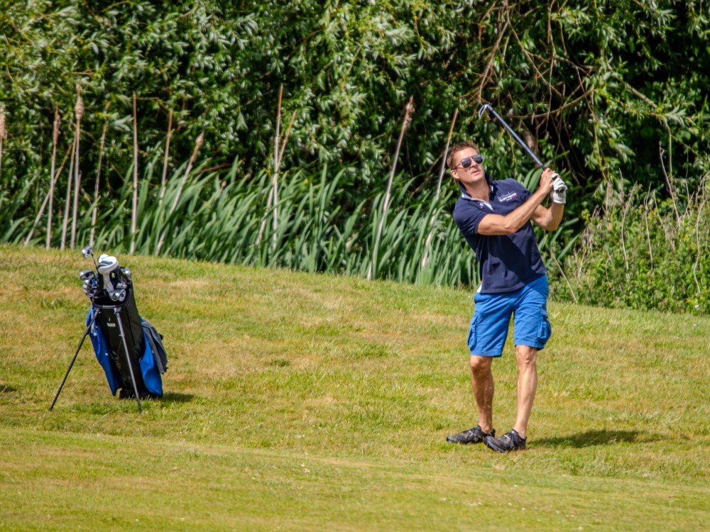 A man on the green swinging a golf club at the Lily Foundation golf day