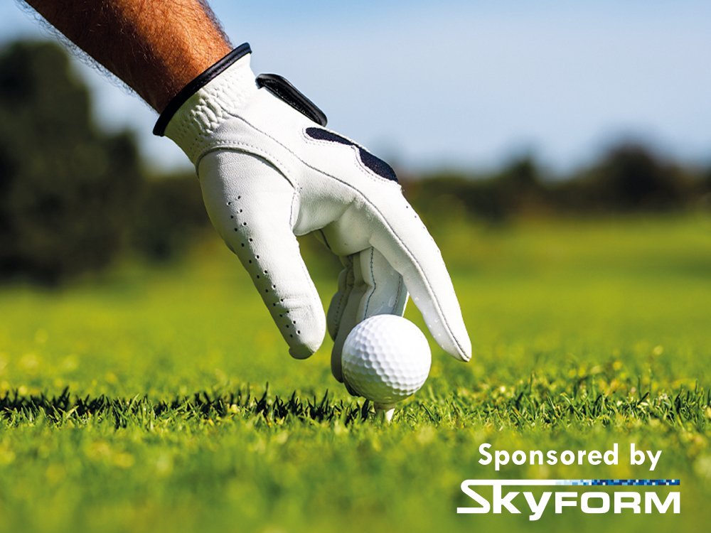 Close-up of a hand in a white glove placing a golf ball onto a tee on the fairway