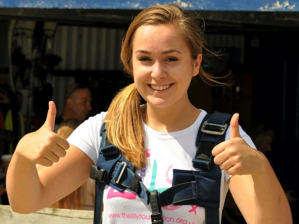 Lily Skydive Weekend 2026 - A woman with a blonde ponytail smiling and giving a thumbs-up to the camera