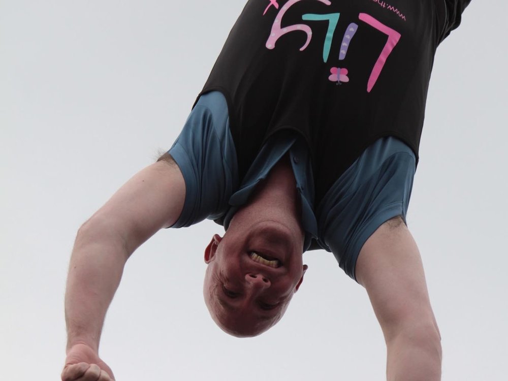 Close up of a man in a Lily Foundation t-shirt upside down mid bungee jump