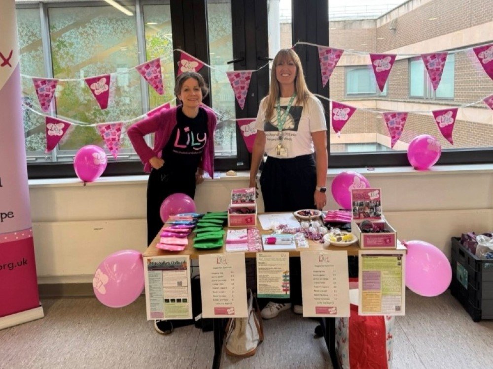 Take a Stand 2026 - Two women in Lily tops standing behind a table decorated with Lily bunting