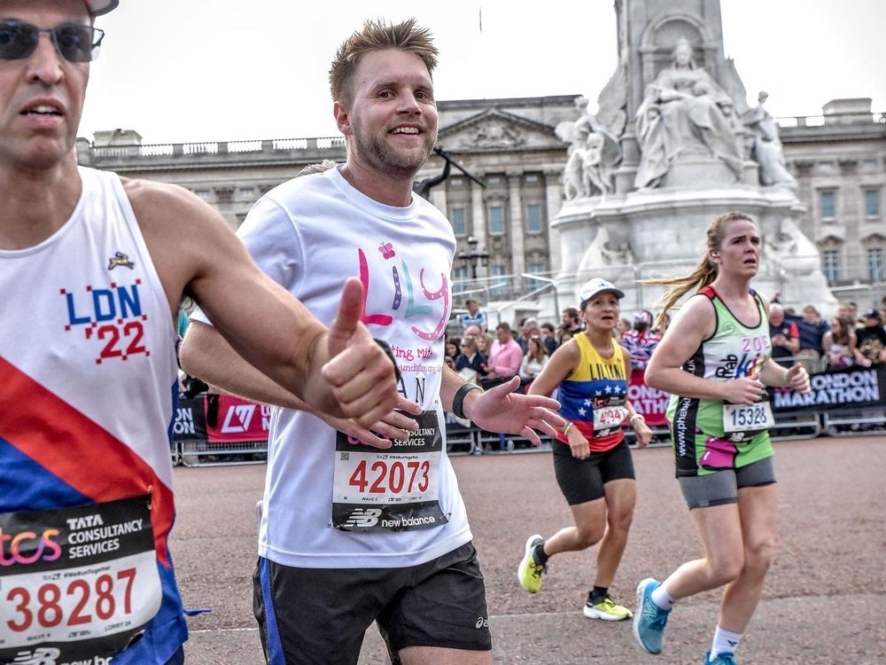A man in a Lily t-shirt running through London with other runners around him