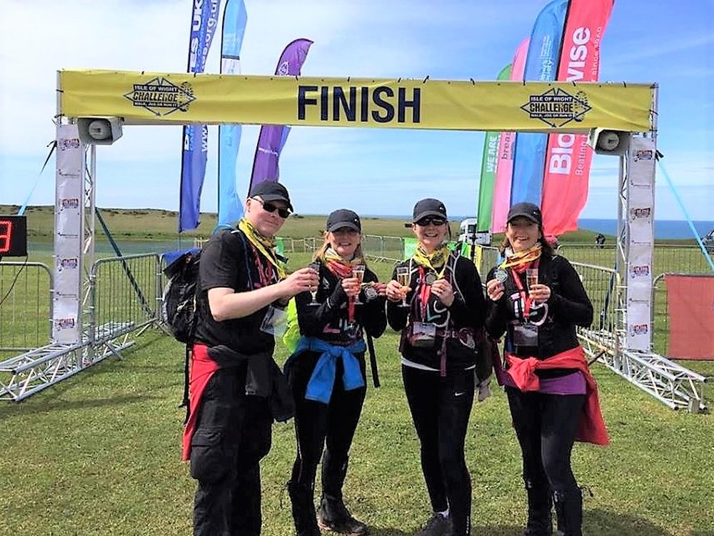 Four Ultra Challenge competitors standing at a finish line with glasses of fizz