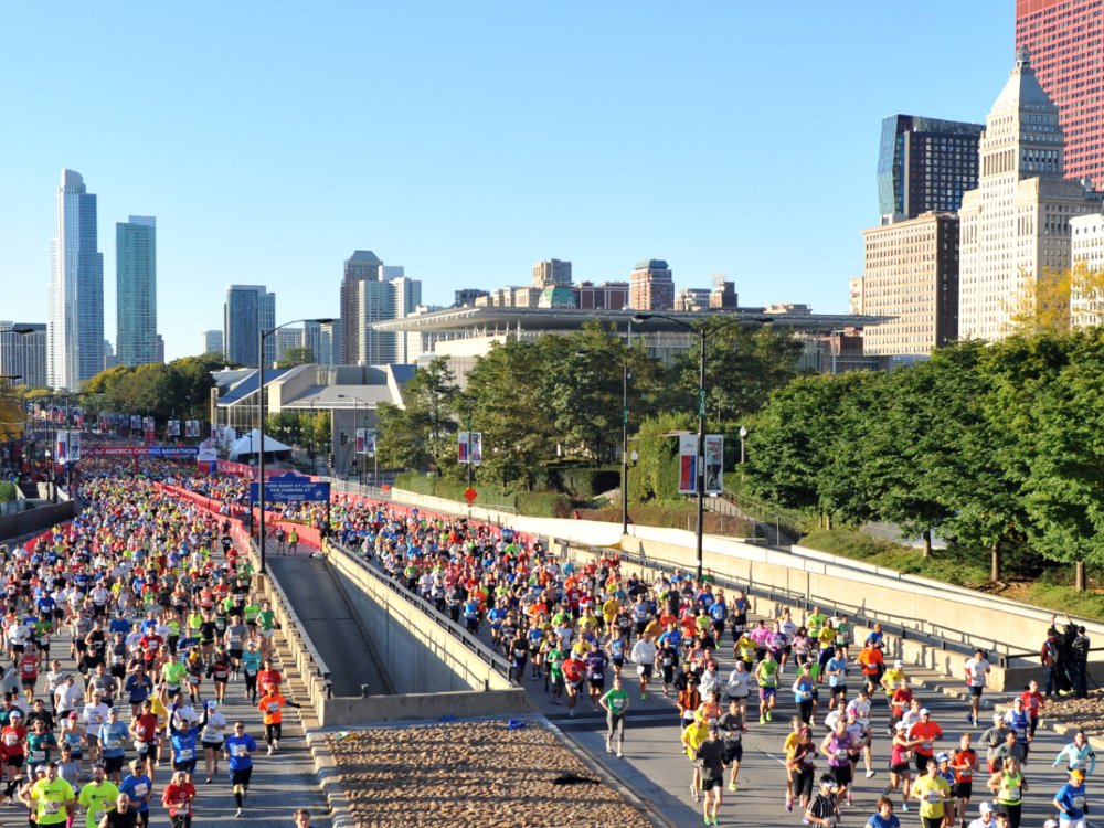 Large group of runners at the start of the Chicago marathon with the city skyline in the distance