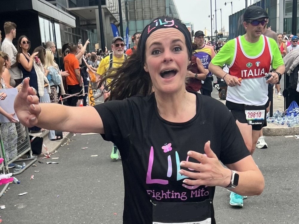 Manchester Marathon 2026 - A lady in a Lily Foundation top waving and smiling at the Manchester Marathon