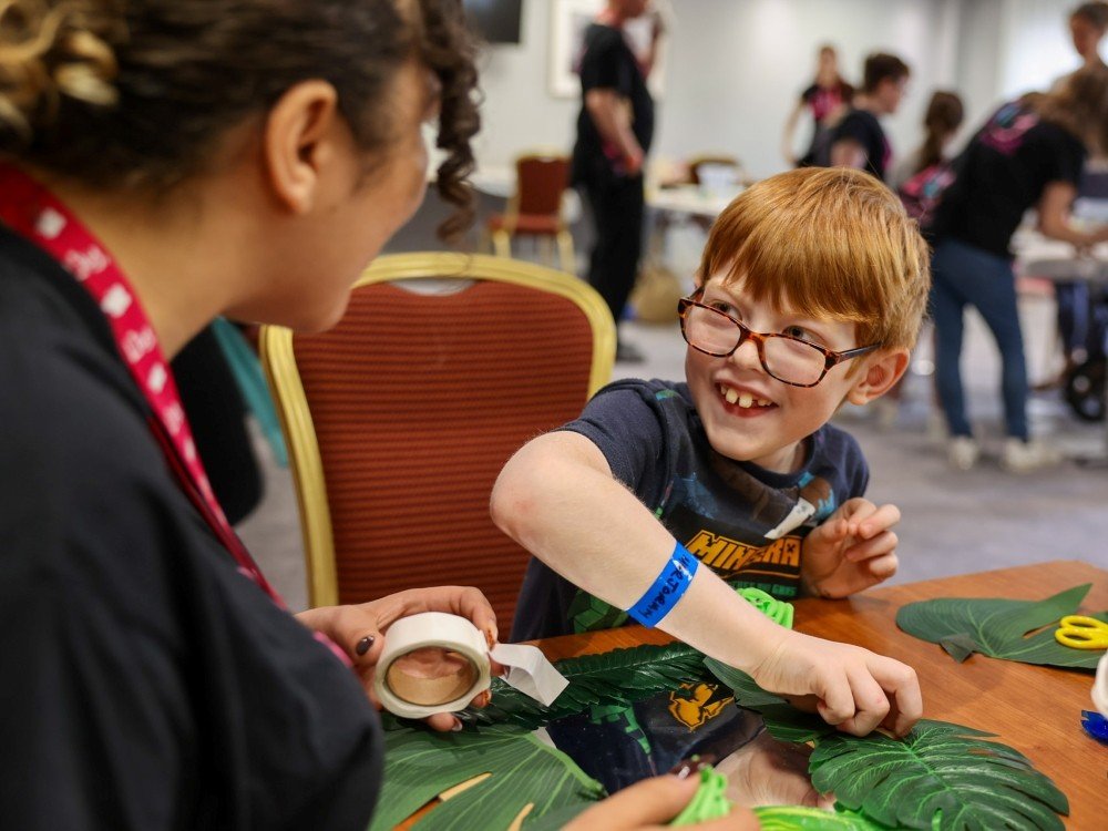 Lily Family Support Weekend 2025 - A young boy at the Lily family support weekend laughing with a volunteer