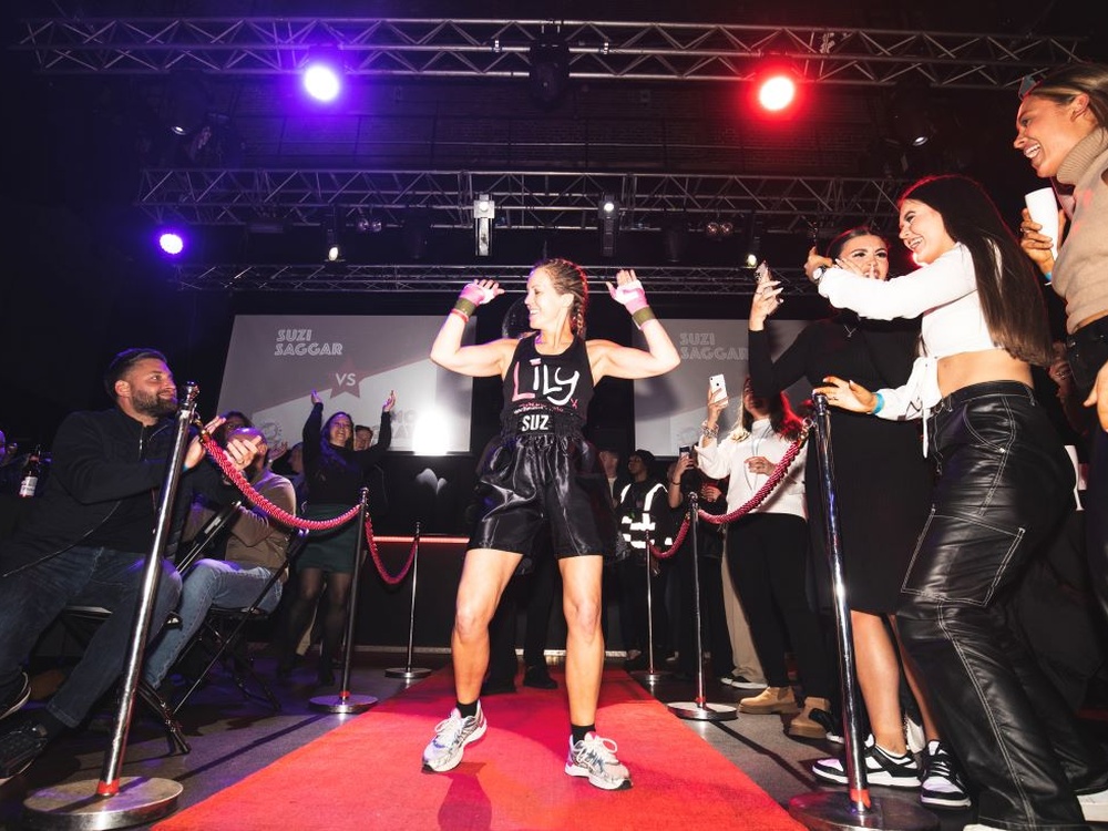 A lady in a Lily vest with her arms up doing her ring walk