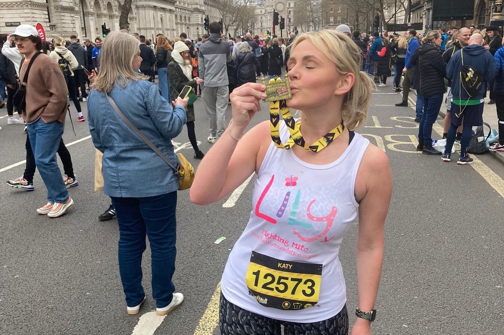 Lady in a Lily Tshirt kissing her London Marathon medal