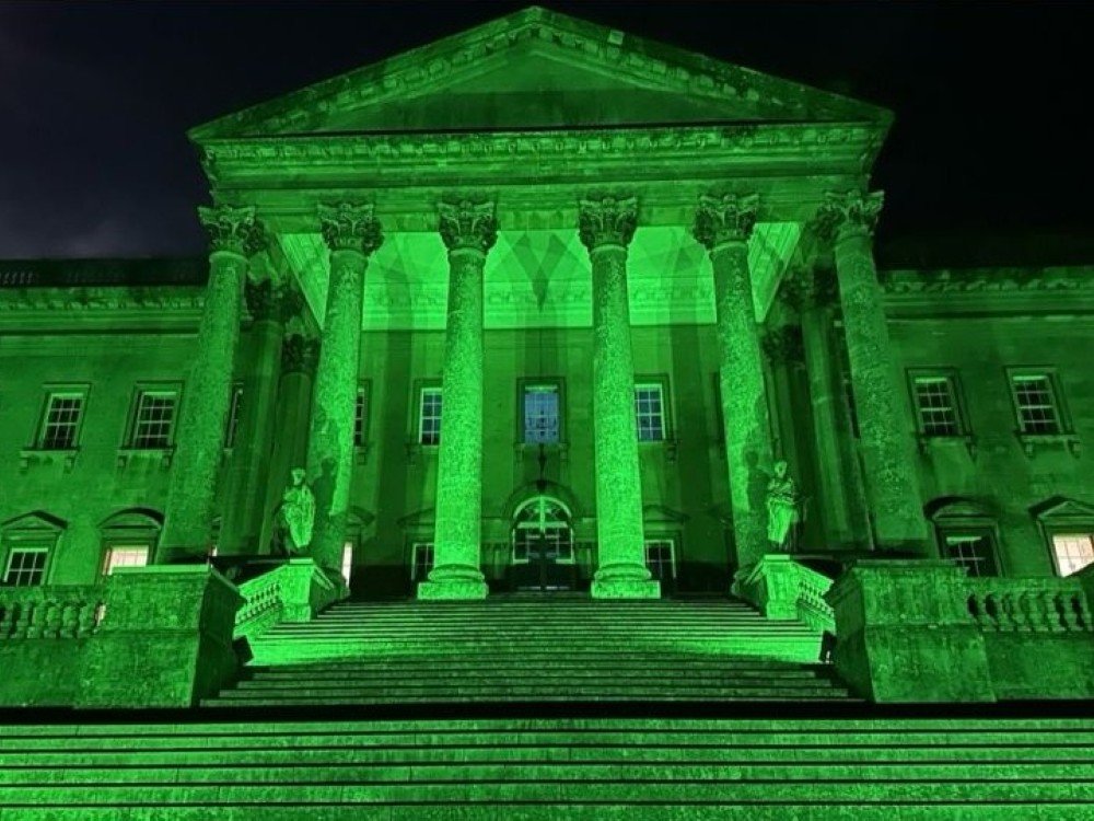 A building with columns and steps at the entrance lit up green