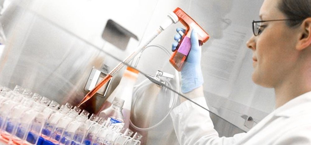 woman in a research lab filing test tubes with an orange liquid
