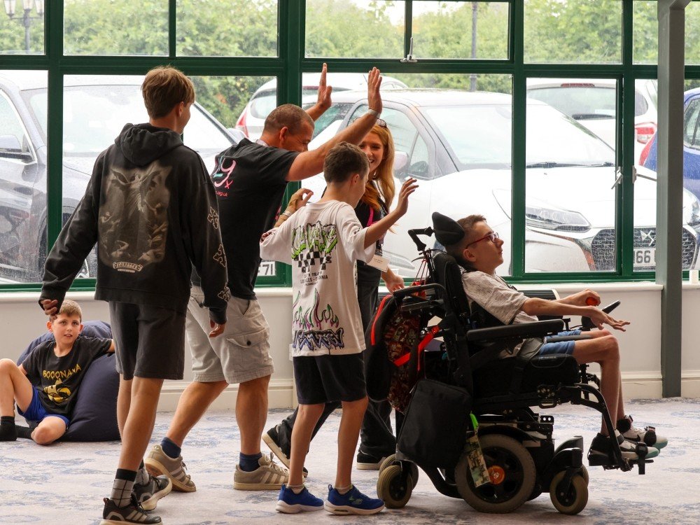 Lily volunteers help a young mito patient in a wheelchair