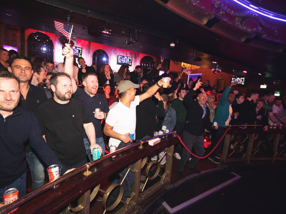 Crowds of spectators on the balcony cheering on the boxers at fight night