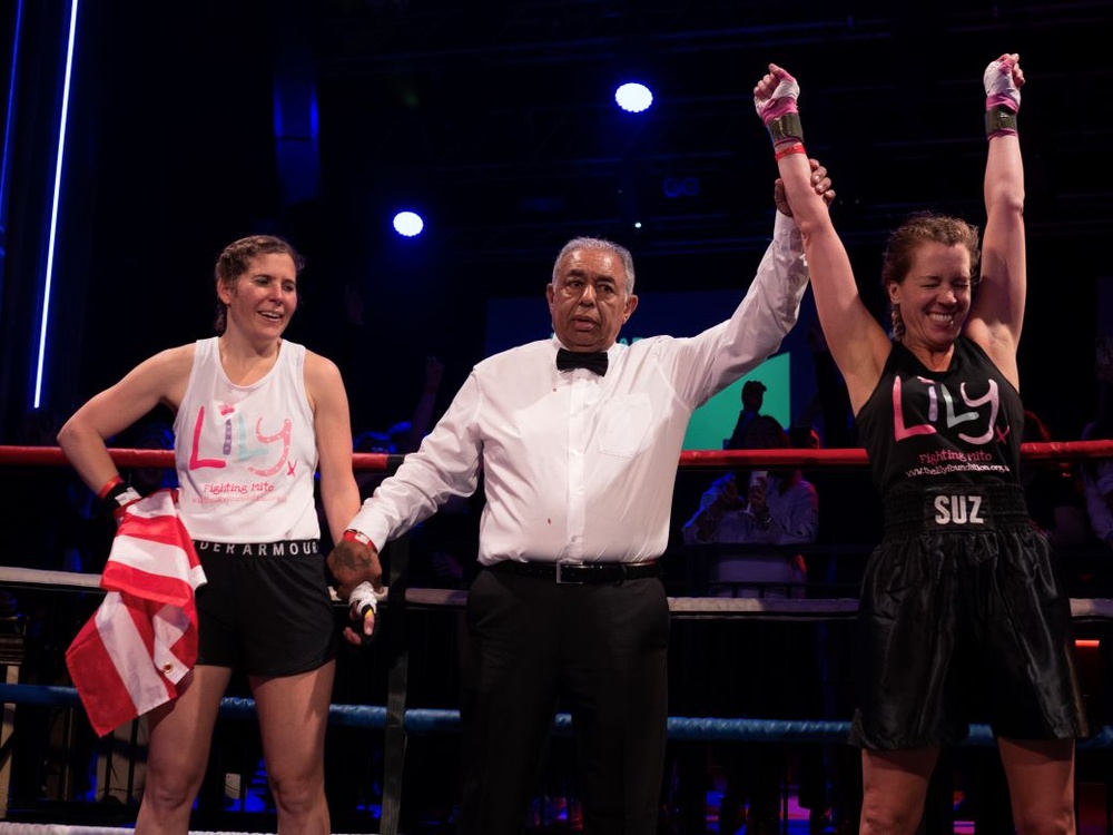 The referee stands between two boxers and holds up the winner's arm