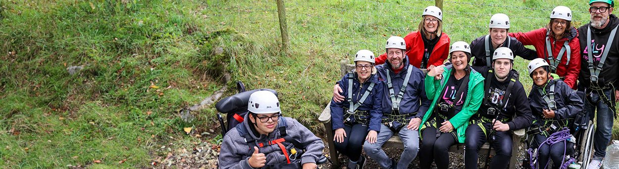 Lily volunteers and young adults with mitochondrial, in orienteering gear about to zip wire in the Lake District
