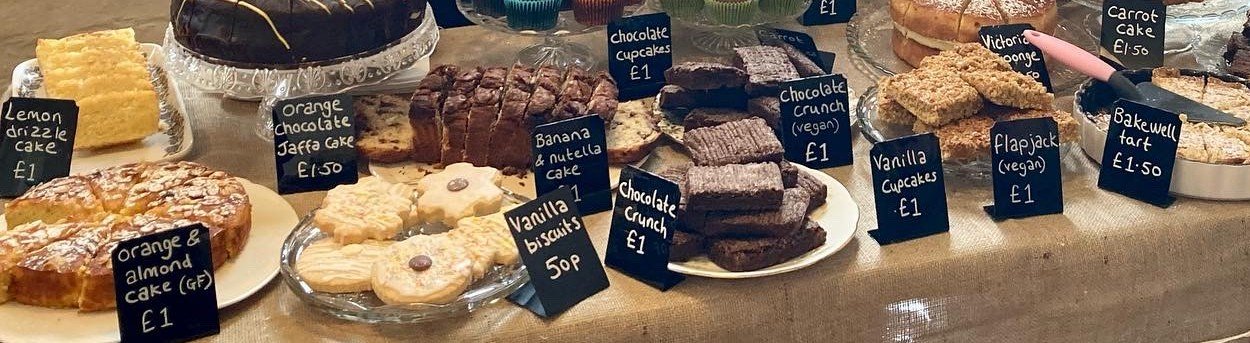 A table laid out with lots of different cakes and treats for a charity bake sale