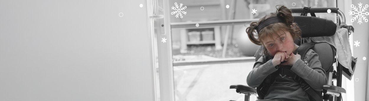 A young mitochondrial disease patient in a wheelchair holding her hands to her mouth