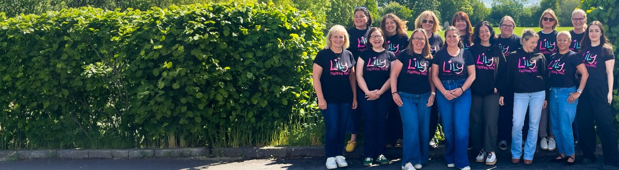 The Lily Foundation team standing together in a row outdoors wearing Lily tops