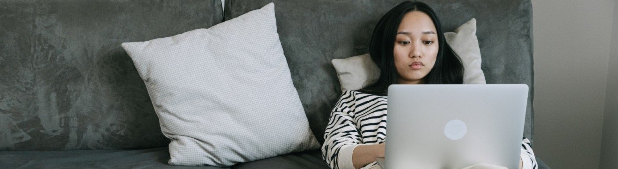 A woman lying on a bed with her laptop on her legs