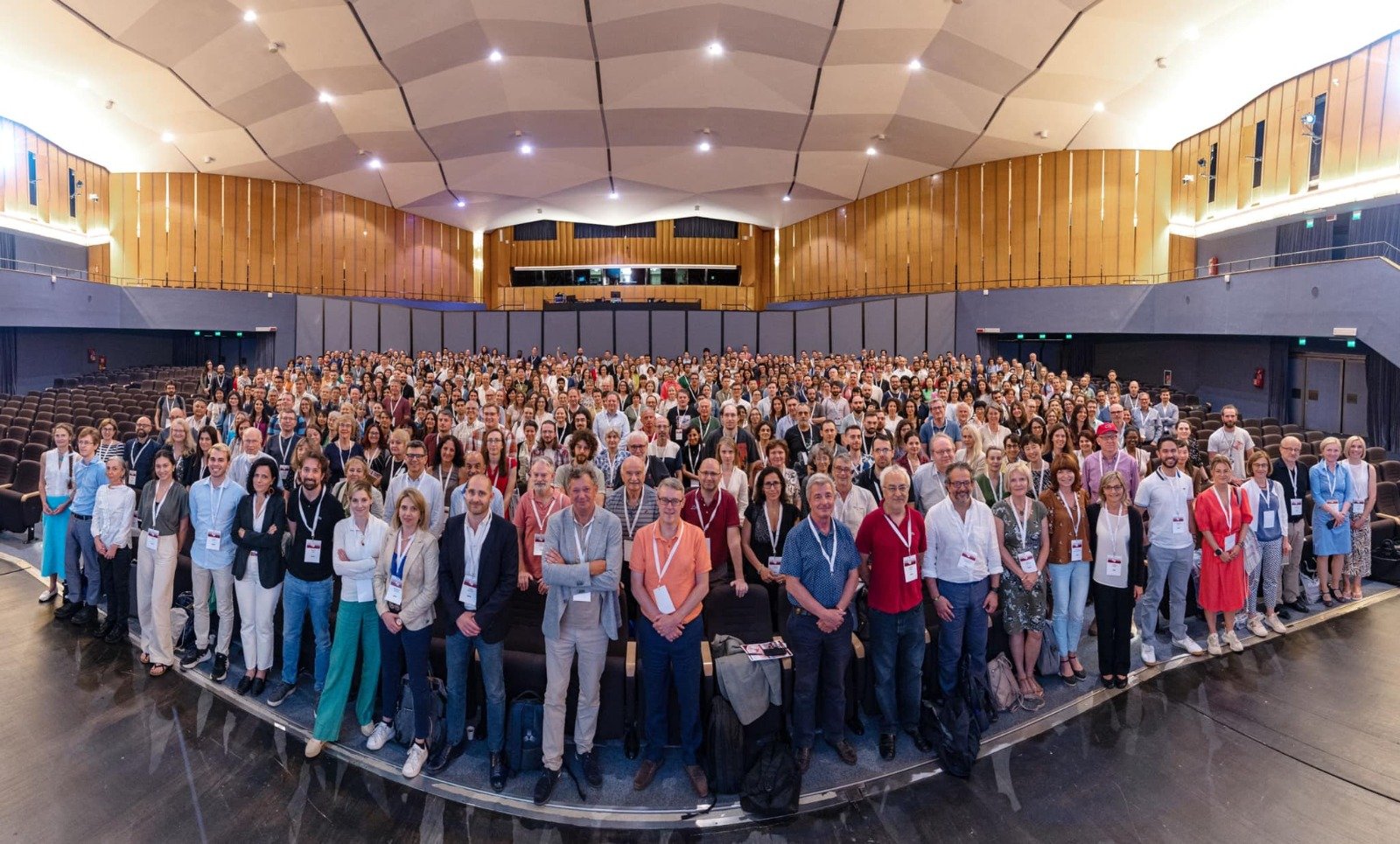 Large crowd of people standing together in a group in a large room at a conference