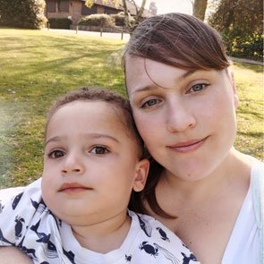 Emma Gibbs, outside in a garden cuddling her young son who has mito