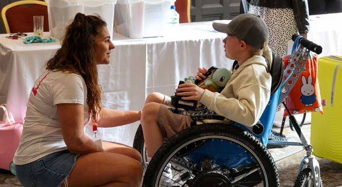 Lily Foundation CEO Liz Curtis kneeling in front of a young mito patient in a wheelchair