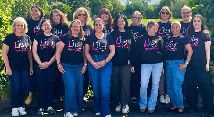 The Lily Foundation team standing together in a row outdoors wearing Lily tops