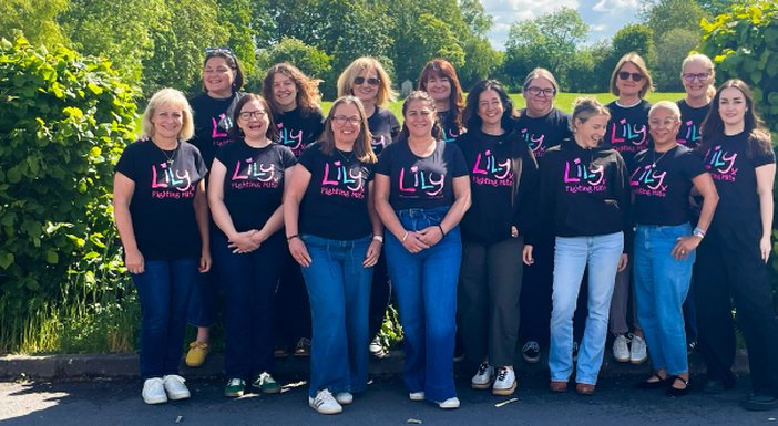The Lily Foundation team standing together in a row outdoors wearing Lily tops