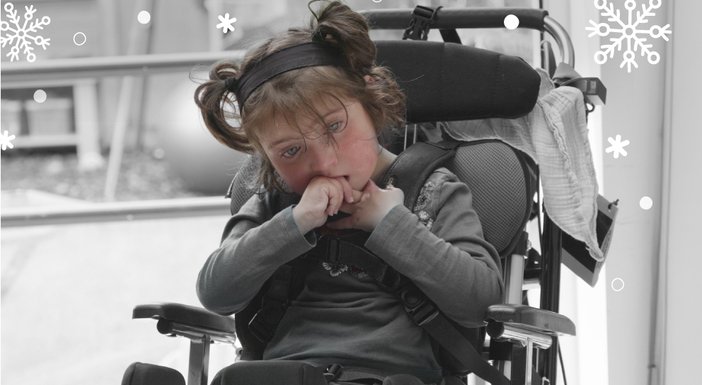 A young mitochondrial disease patient in a wheelchair holding her hands to her mouth