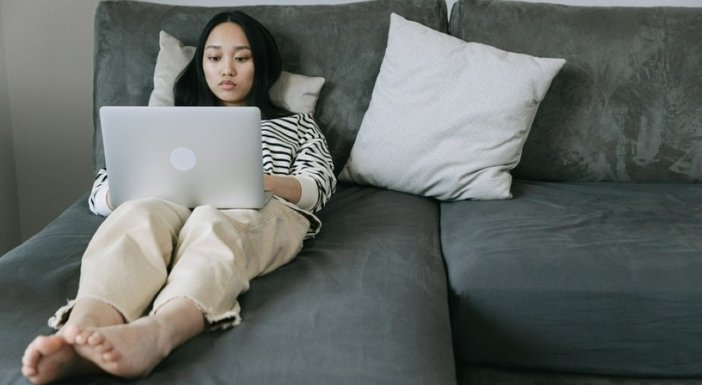 A woman lying on a bed with her laptop on her legs