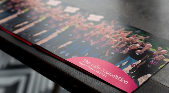 A pile of Lily Foundation impact reports laid out on a desk