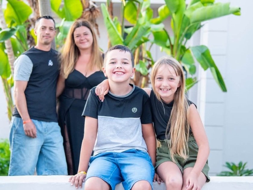 Mito patient Fletcher sitting next to his sister with his parents standing in the background