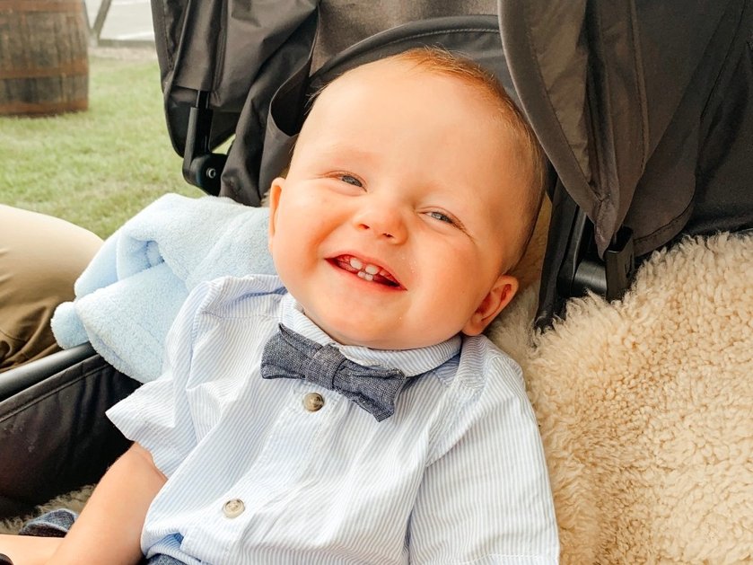 A young baby with mitochondrial disease smiling in his buggy