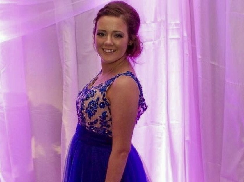 A young girl in a sparkly blue balldress smiling and posing for the camera